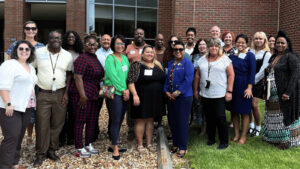 Diverse group of 21 public health professionals posting outside a building