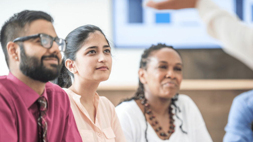 Three diverse individuals looking at a speaker