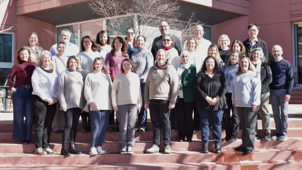Group photo of APHLI Scholars standing on outdoor steps in front of a modern building during APHLI retreat