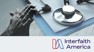 a hand in prayer next to a stethoscope on a clipboard with the Interfaith America logo at the bottom of the image