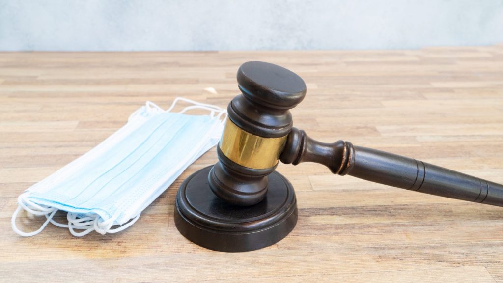 gavel and a surgical mask on a wooden table